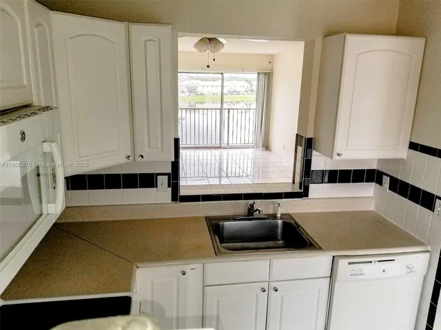 a kitchen with a sink a stove and white cabinets