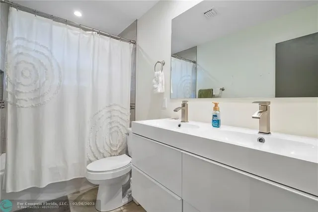 a bathroom with a sink a toilet and shower curtain