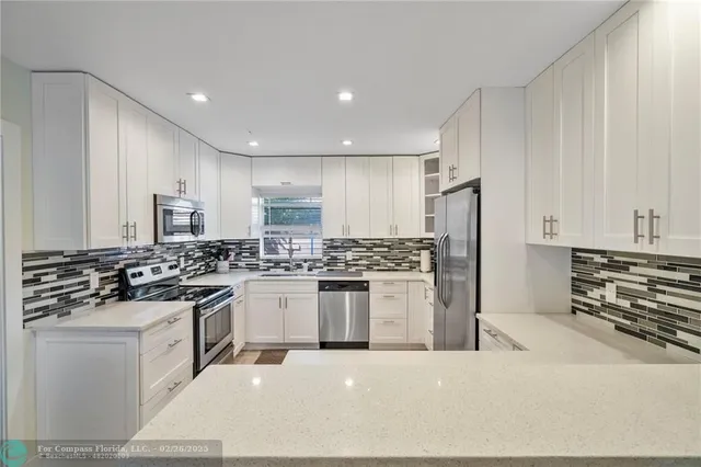 a kitchen with stainless steel appliances a stove a sink a refrigerator and white cabinets