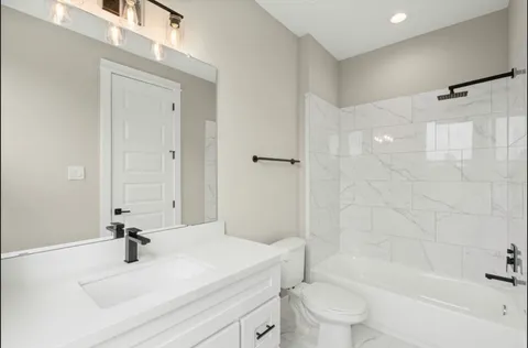 a bathroom with a bathtub shower sink vanity and toilet