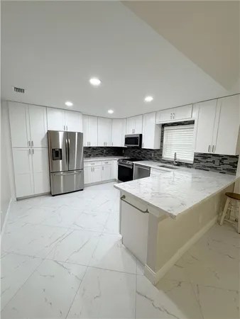a large kitchen with stainless steel appliances kitchen island granite countertop a refrigerator and a stove top oven