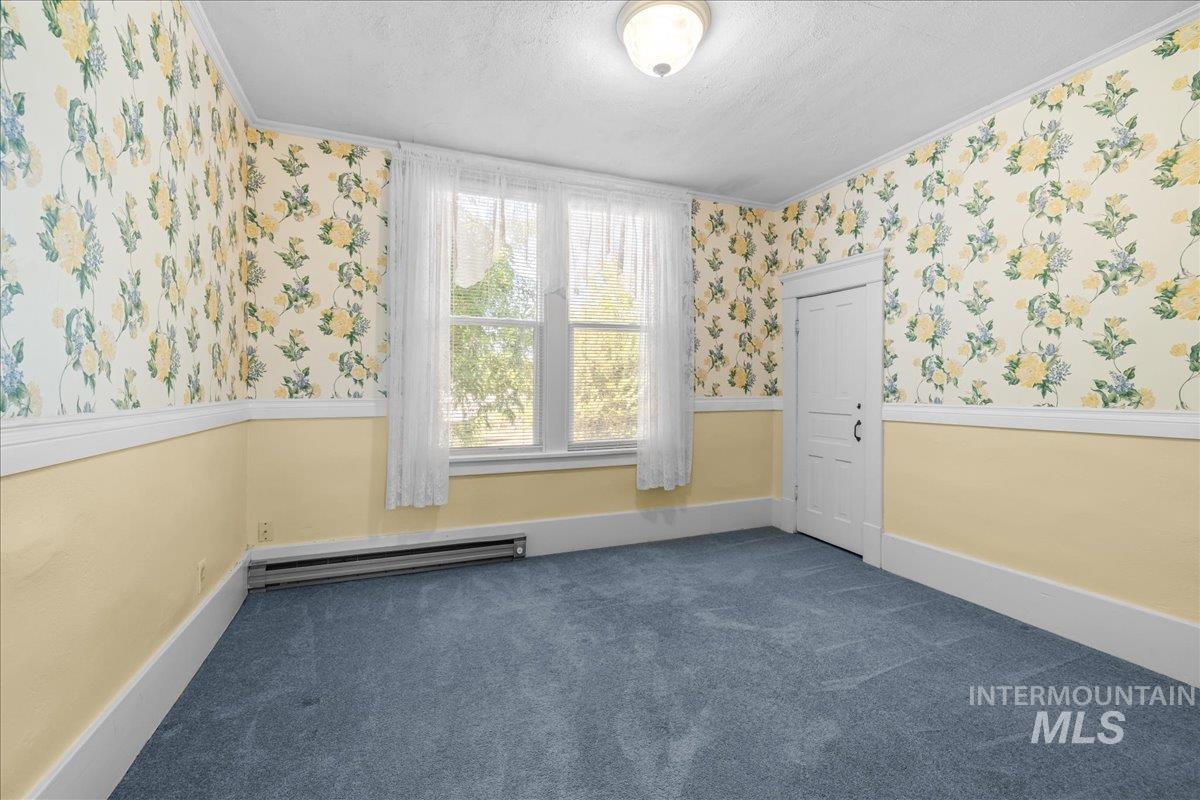 5611 West Hill Road Boise, ID 83703 - Photo 30 of 48 Spare bedroom with wallpapered walls, dark carpet, ornamental molding, a textured ceiling, and a baseboard heating unit
