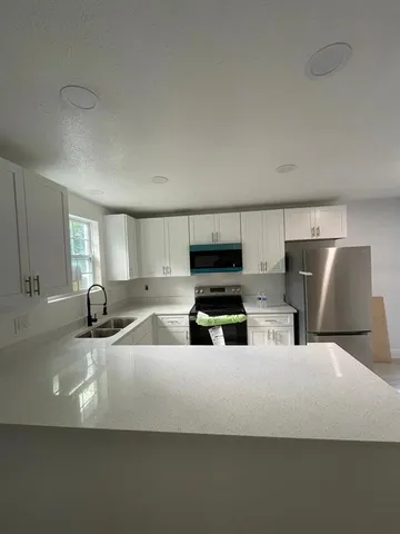a kitchen with stainless steel appliances a microwave a sink and white cabinets