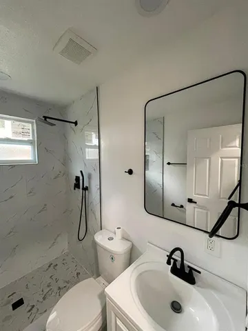 a bathroom with a sink a toilet and shower