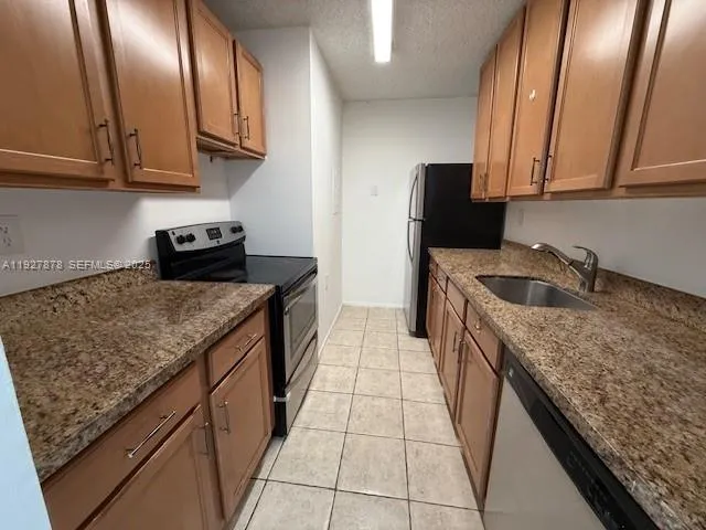 a kitchen with granite countertop stainless steel appliances a sink stove and cabinets