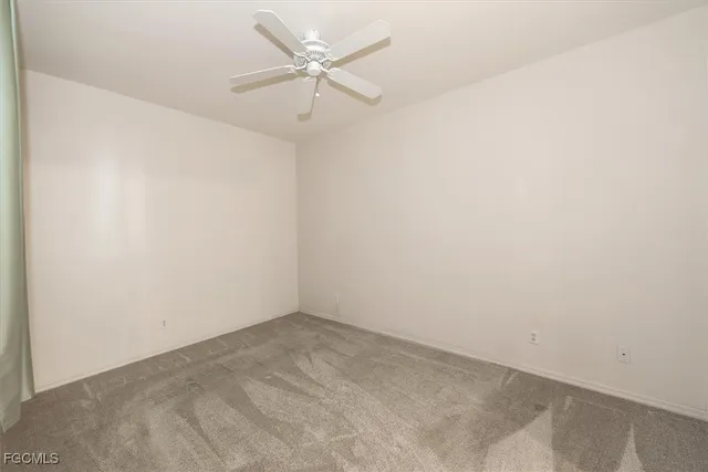 an empty room with a fan & a ceiling fan
