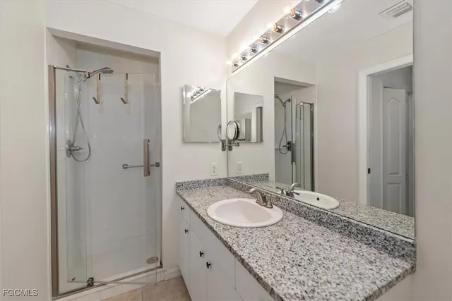a bathroom with a granite countertop sink a mirror and shower