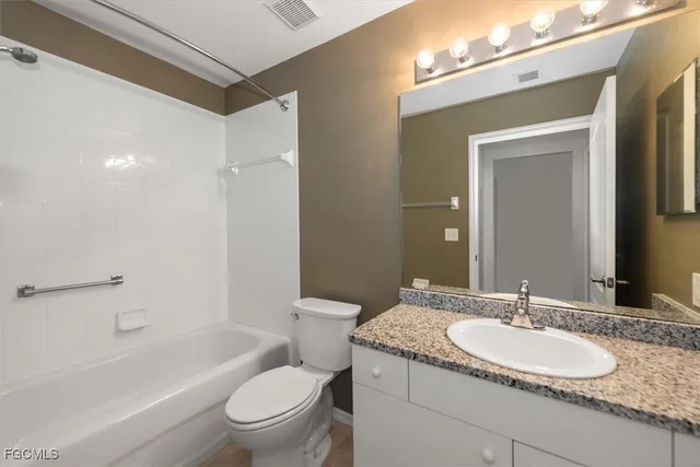 a bathroom with a granite countertop sink a toilet and a large mirror