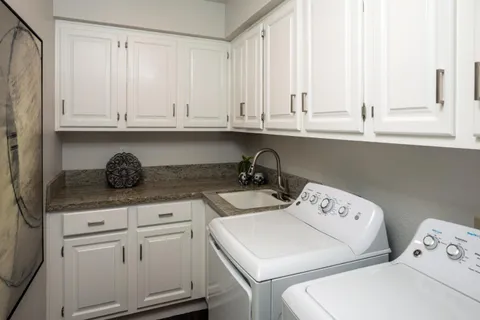 a kitchen with white cabinets and sink