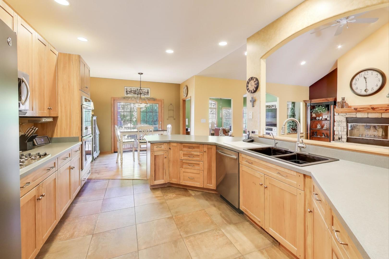9206 Pine Needle Pass Bull Valley, IL 60097 - Photo 9 of 44 a large kitchen with stainless steel appliances kitchen island granite countertop a large stove top oven and large windows