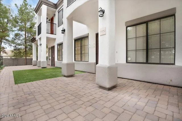 a view of a white building with a potted plant and a yard