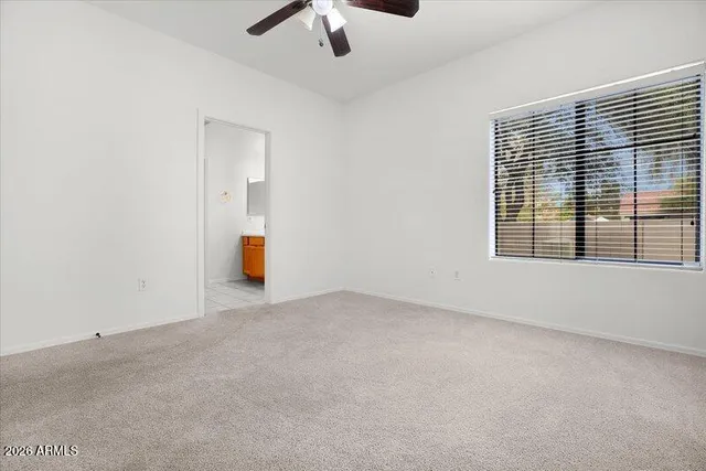 an empty room with a ceiling fan and carpet