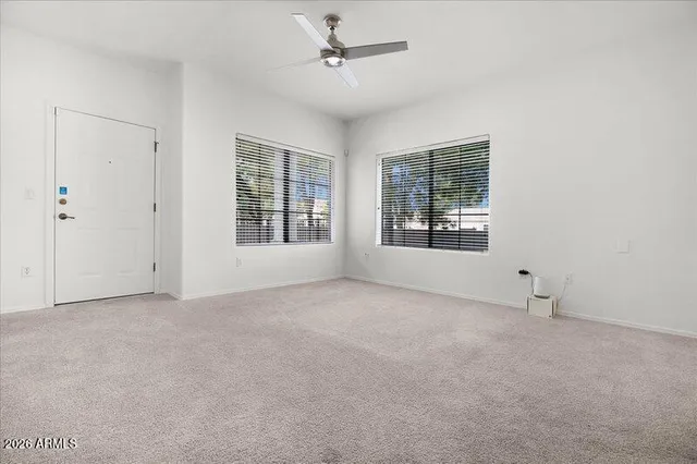 an empty room with chandelier fan and windows
