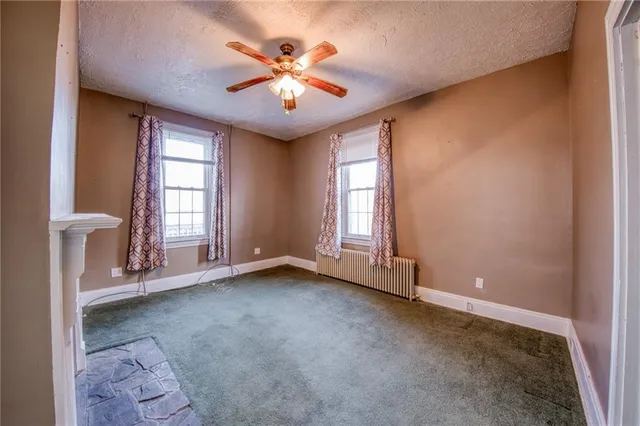 an empty room with windows and chandelier fan