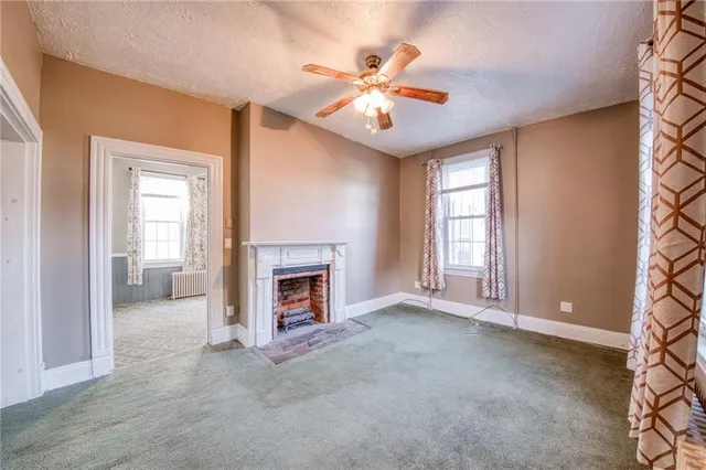 a view of an empty room with chandelier fan and fire place