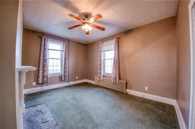 an empty room with windows and chandelier fan