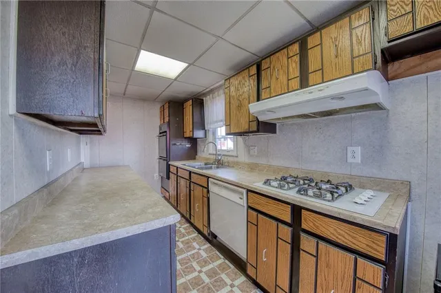 a kitchen with stainless steel appliances granite countertop a stove a sink dishwasher and cabinets with wooden floor