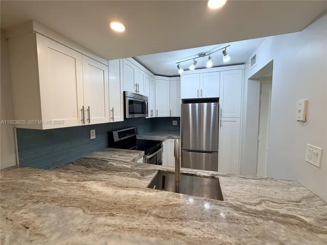 a kitchen with kitchen island a counter top space cabinets and stainless steel appliances