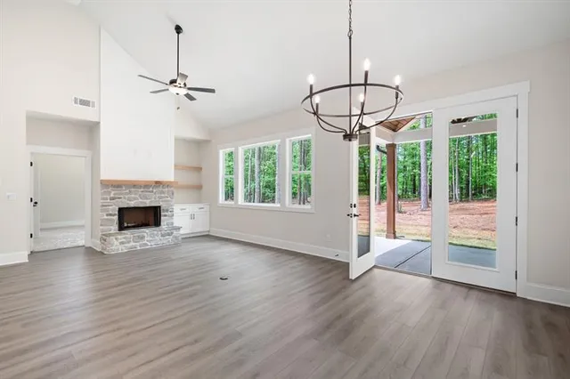 an empty room with windows fireplace and wooden floor