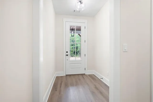 a view of an empty room with window and wooden floor