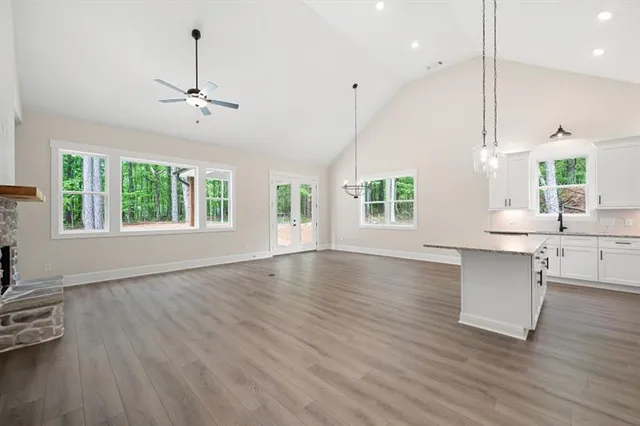 a kitchen with stainless steel appliances granite countertop a sink a stove a refrigerator and island with wooden floor