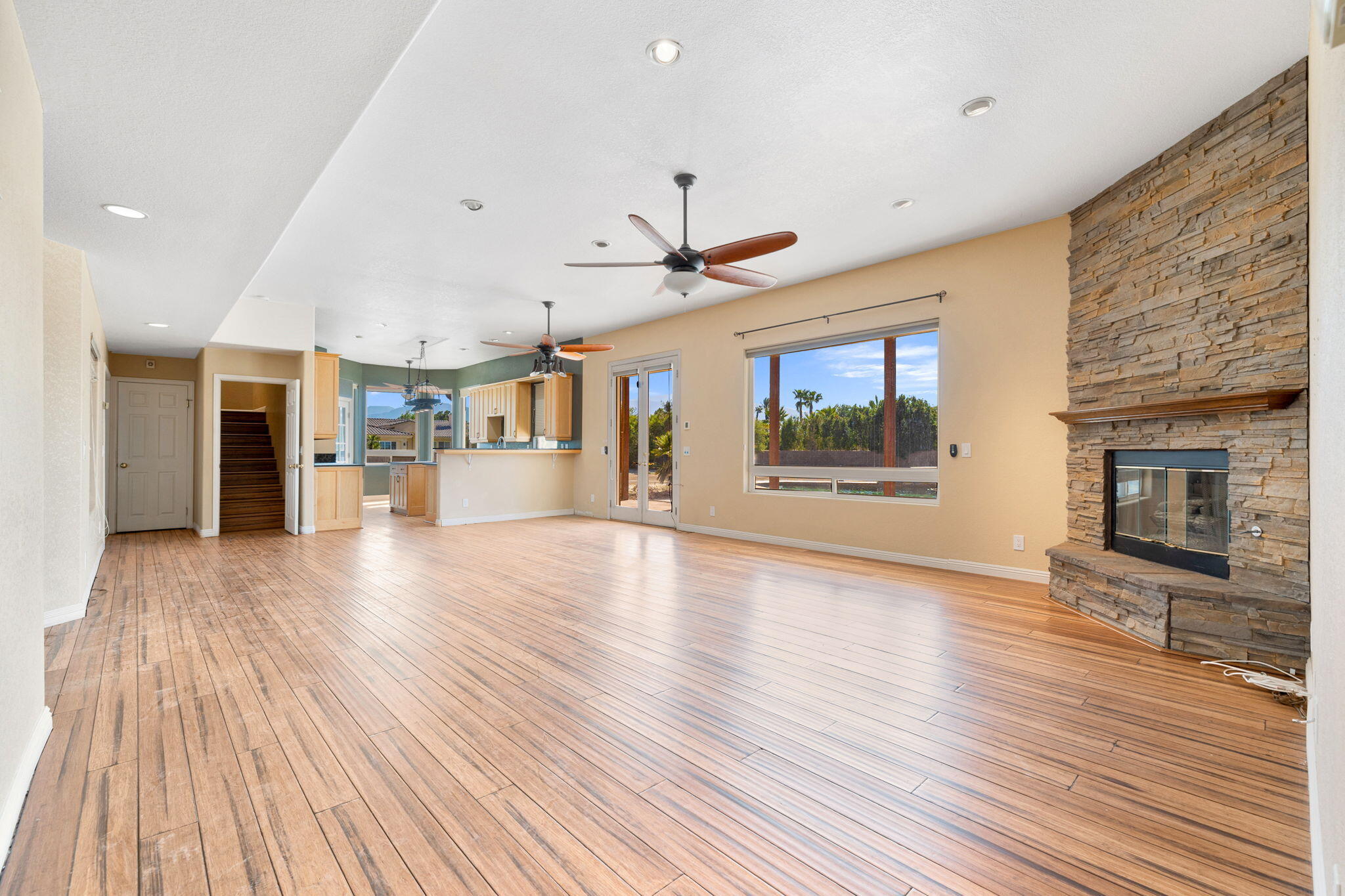 48755 Southview Place Indio, CA 92201 - Photo 33 of 55 an empty room with wooden floor a ceiling fan a kitchen view and a large window