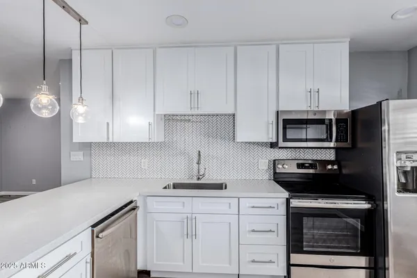 a kitchen with white cabinets and stainless steel appliances