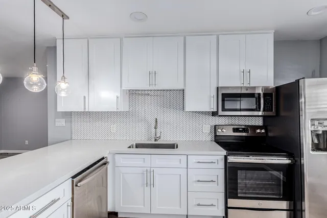a kitchen with white cabinets and stainless steel appliances