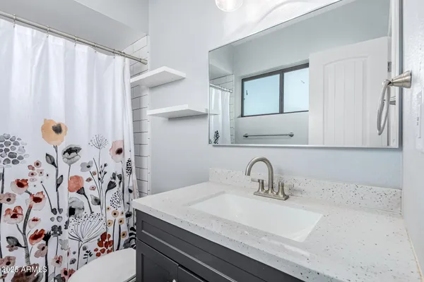 a bathroom with a sink a mirror and shower curtain