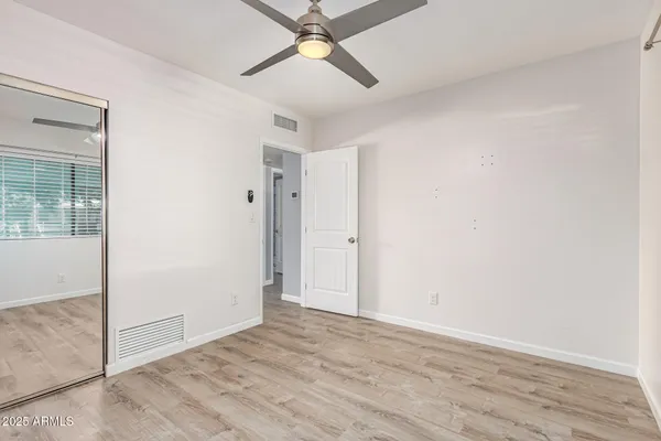 an empty room with wooden floor fan and windows