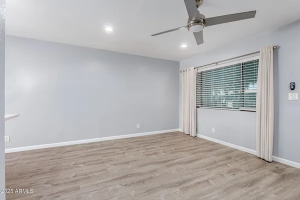 a view of an empty room with wooden floor and a window