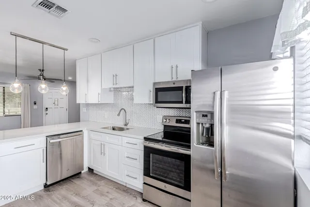 a kitchen with white cabinets and stainless steel appliances