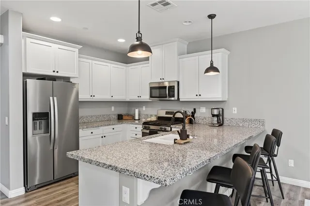 a kitchen with stainless steel appliances granite countertop a sink a stove a refrigerator cabinets and chairs