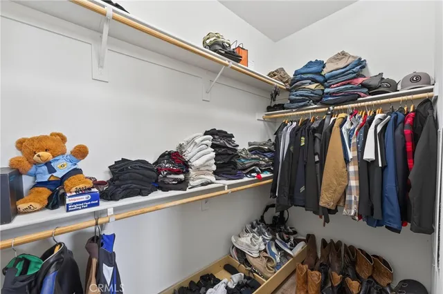 a view of walk in closet with clothes and shoes