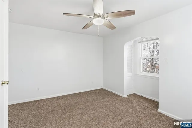 an empty room with windows and fan