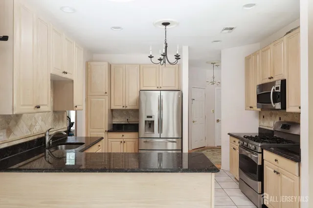 a kitchen with stainless steel appliances granite countertop a refrigerator a stove and a sink with wooden floor
