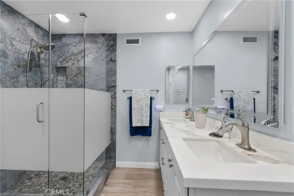 a bathroom with a double vanity sink a mirror and shower