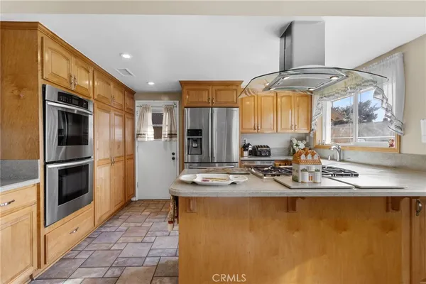 a kitchen with stainless steel appliances granite countertop a sink a stove a refrigerator and a dining table
