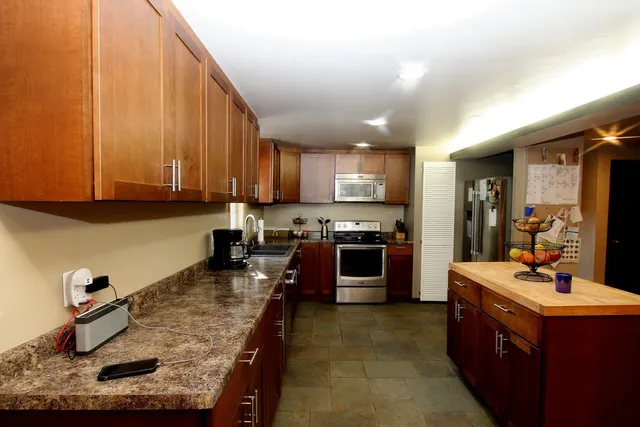 a kitchen with kitchen island granite countertop a sink stove and refrigerator