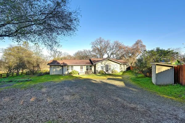 a view of a house with a yard and large trees