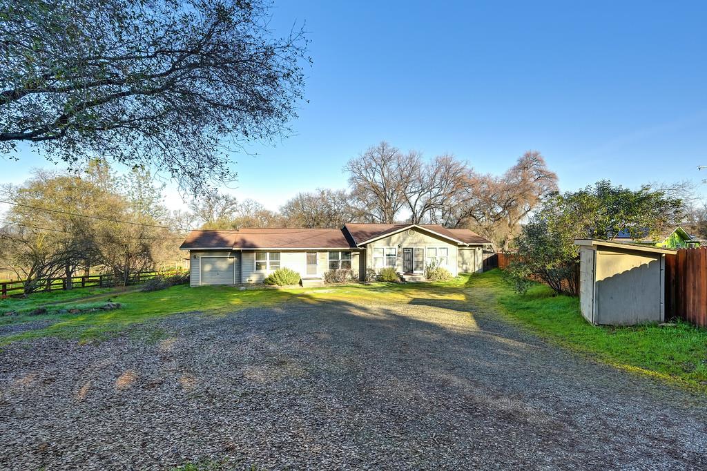 a view of a house with a yard and large trees
