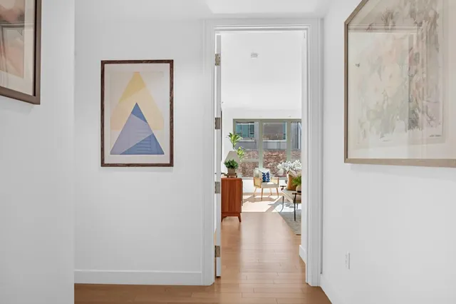 a view of a hallway with wooden floor and a dining room with furniture