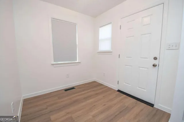 an empty room with wooden floor and windows