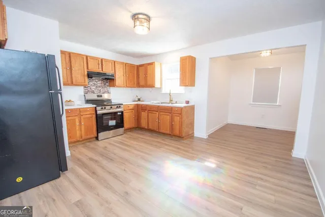 a large kitchen with stainless steel appliances granite countertop a stove a sink dishwasher and a refrigerator with wooden floor