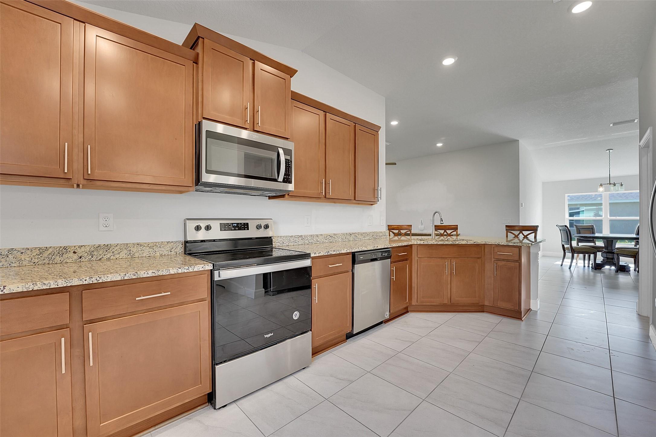 8600 Merano Avenue Fort Pierce, FL 34951 - Photo 9 of 22 a kitchen with granite countertop a stove top oven microwave and cabinets