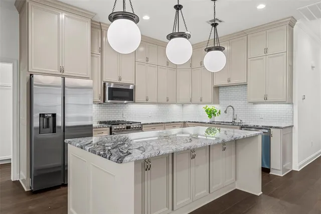 a kitchen with stainless steel appliances granite countertop a sink a stove refrigerator and cabinets