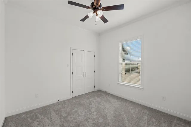 an empty room with chandelier fan and windows