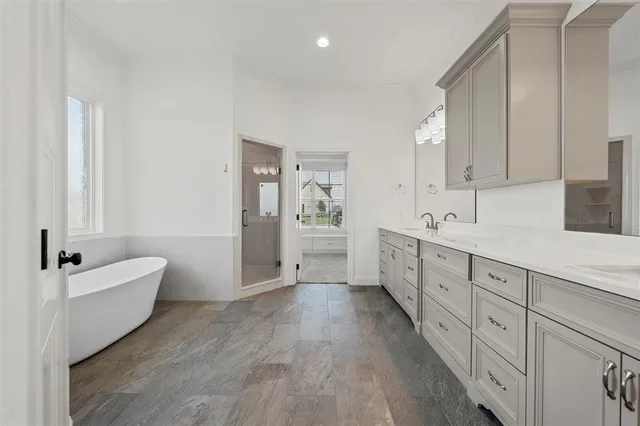 a spacious bathroom with double vanity a large mirror and a bathtub