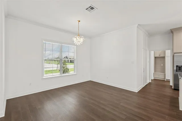 an empty room with wooden floor chandelier and windows