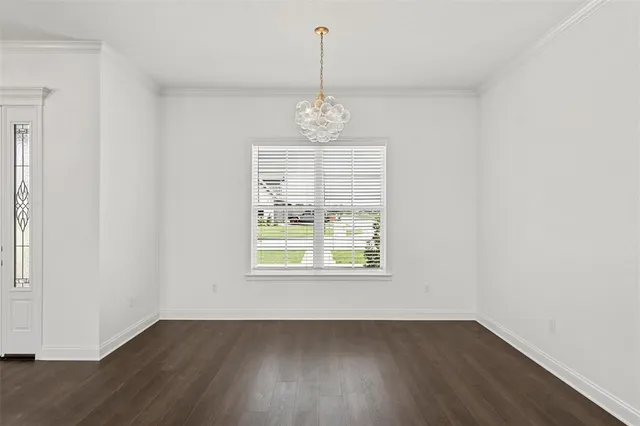 an empty room with wooden floor windows and hallway